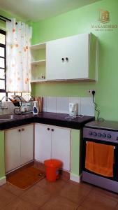 Una cocina con gabinetes blancos y una estufa. en Makasembo breeze homes, en Kisumu