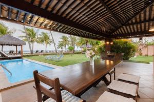 ein Esszimmer mit einem Tisch und einem Pool in der Unterkunft Casa Mar: vista e acesso à praia | By Carpediem in Jacumã