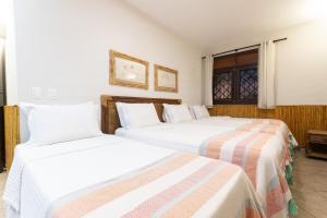 zwei Betten in einem Zimmer mit weißen Wänden in der Unterkunft Casa Mar: vista e acesso à praia | By Carpediem in Jacumã