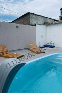 zwei Stühle und ein Pool neben einem Gebäude in der Unterkunft Bertioga Rio da Praia in Bertioga