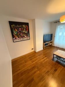 un salon avec un tableau au mur et une télévision dans l'établissement Appartement, à Saint-Michel-de-Maurienne