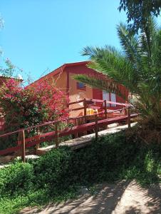 a wooden fence in front of a building with pink flowers at Lodge Gabriela Mistral in Pisco Elqui