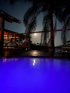 a view of a pool at night with palm trees at Casa 5 suítes - Vista para a Barra do Sahy in São Sebastião