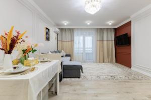 ein Wohnzimmer mit Tisch und Couch in der Unterkunft Шикарные апартаменты возле Хан Шатыр in Astana