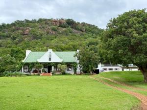 a white house with a green roof and a hill at La Ronel Guest Farm in Roossenekal