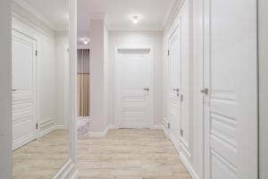 einen Flur mit weißen Türen und Holzböden in der Unterkunft Шикарные апартаменты возле Хан Шатыр in Astana