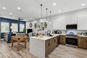 a kitchen and living room with white cabinets and a table at The Larimar 2BD TownHouse 7ST Walkable in Fort Worth