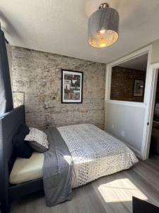 a bedroom with a bed and a brick wall at Historic Downtown Apartment 2BD Retreat in London
