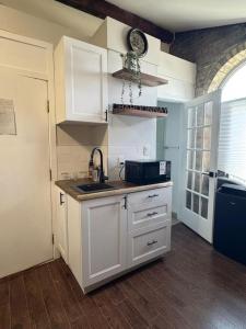 a kitchen with white cabinets and a sink and a microwave at Historic Downtown Apartment 2BD Retreat in London +9 photos