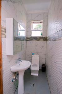 a white bathroom with a sink and a toilet at Elegant Lakeside Villa in Kibuye, Rwanda in Mwendo