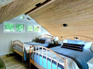 zwei Betten in einem Schlafzimmer mit Holzdecke in der Unterkunft Beachfront cabin, dock, water views in Point White