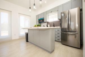 a kitchen with a stainless steel refrigerator and white cabinets at Sunset Villas in Crawfish Rock