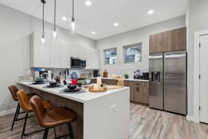 a kitchen with white cabinets and a large island with bar chairs at The Opal 2BD TowenHouse 7ST Walkable in Fort Worth