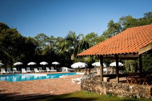 a swimming pool with umbrellas and chairs and a resort at Pousada do Quilombo in São Bento do Sapucaí