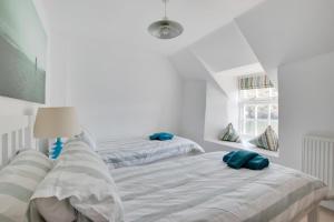 zwei Betten in einem weißen Zimmer mit blauen Kissen darauf in der Unterkunft Stepaside Cottage in Fowey