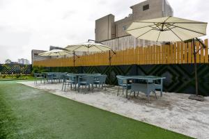 Un grupo de mesas y sillas con sombrillas. en Hotel O Park Land, en Zirakpur