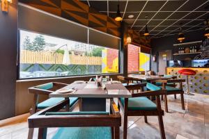 Un restaurante con mesas y sillas de madera y un gran ventanal. en Hotel O Park Land, en Zirakpur