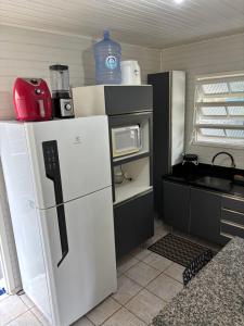 a small kitchen with a refrigerator and a microwave at Casa na Beira Mar Continental in Florianópolis