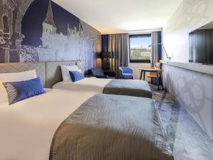 a hotel room with two beds and a tv at Mercure Budapest Castle Hill in Budapest