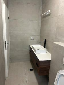 a white bathroom with a sink and a toilet at Yarin's apartment in Qiryat Shemona