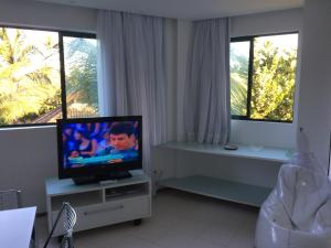 a living room with a tv and two windows at Marulhos Resort Muro Alto Studio in Porto De Galinhas
