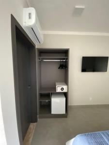 Un dormitorio con una cama y un televisor en una habitación. en Uberlândia Suítes Hotel, en Uberlândia 35 fotos más