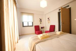 a bedroom with two red chairs and a bed at Sirocco in Kissamos