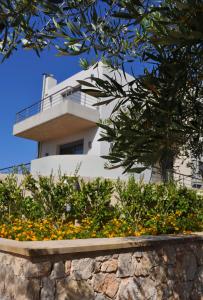 a white house behind a stone wall with flowers at Sirocco in Kissamos