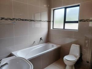 een badkamer met een bad, een toilet en een wastafel bij Agapantha Cottage in Ezulwini