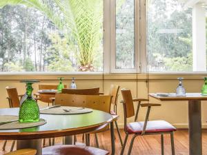 een restaurant met tafels en stoelen met groene vazen erop bij Hotel ibis Porto Sul Europarque in Santa Maria da Feira