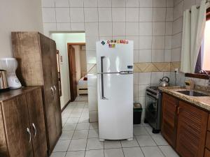 a kitchen with a white refrigerator in a kitchen at Partiu Praia SC- Piscina, Ar condicionado, wi-fi, duas quadras da praia e centrinho in Pinheiro