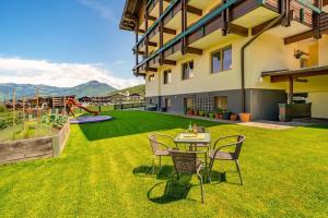 a patio with a table and chairs on a lawn at Appartement Nr 2 Haus Voglreiter in Kaprun