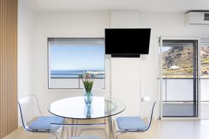 a dining room with a glass table with chairs and a television at Salitre - Armonía Park, Bajamar in La Laguna