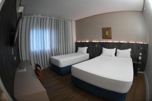 a hotel room with two beds and a window at Nacional Palace Hotel in Corumbá +18 photos