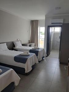 Una habitación de hotel con tres camas en una habitación. en Uberlândia Suítes Hotel, en Uberlândia