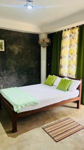 a bedroom with a large bed with green curtains at Homestead Villa-Polwatta in Welihinda