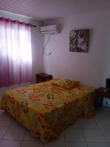 a bedroom with a bed with a yellow blanket at Les jardins de VALENTIN in Le Gosier