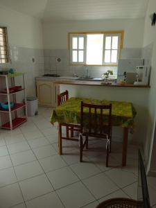 a kitchen with a table and chairs in a room at Les jardins de VALENTIN in Le Gosier