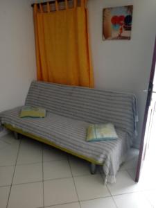 a couch with two pillows sitting in a room at Les jardins de VALENTIN in Le Gosier