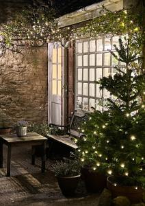 eine Terrasse mit Weihnachtsbaum, Bank und Fenster in der Unterkunft Four Seasons Cottage - in the Cotswolds in Tewkesbury