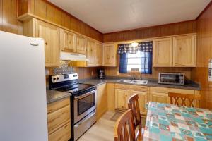 a kitchen with wooden cabinets and a table and a sink at Pet-Friendly Cabin with Designated Boat Slip! in Fairfield Bay +19 photos
