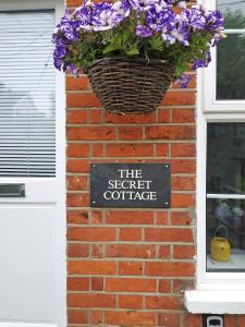 a sign on a brick wall with a basket of flowers at Colchester, Cosyquietopen Firepatiopetstrain in Wivenhoe +6 photos