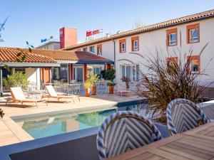 a patio with chairs and a pool and a building at ibis Montauban in Montauban