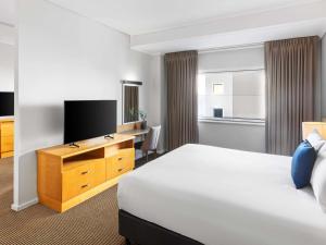 a hotel room with a bed and a desk at Novotel Perth Langley in Perth