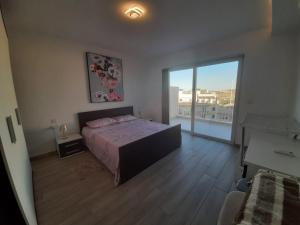 een slaapkamer met een bed en een groot raam bij Sunsets Duplex Penthouse Gozo in Kerċem +19 foto's