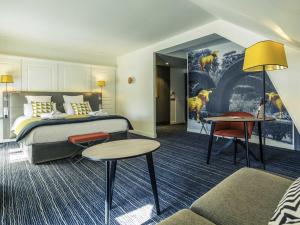 a hotel room with a bed and a table and chairs at Hotel De Bourbon Grand Hotel Mercure Bourges in Bourges