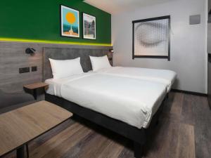 a large bed in a room with a green wall at ibis Styles London Gatwick Airport in Crawley