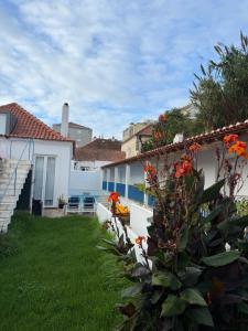 Un patio trasero de una casa con césped verde y flores naranjas. en Pátio Prior do Crato 4, en Almada