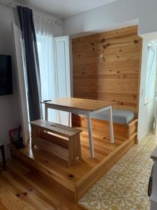 Una mesa y un banco en una habitación con una pared de madera. en Pátio Prior do Crato 4, en Almada
