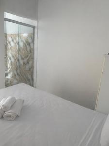 a white bed with two rolled towels on it at ElRancho Suites in Itaparica Town